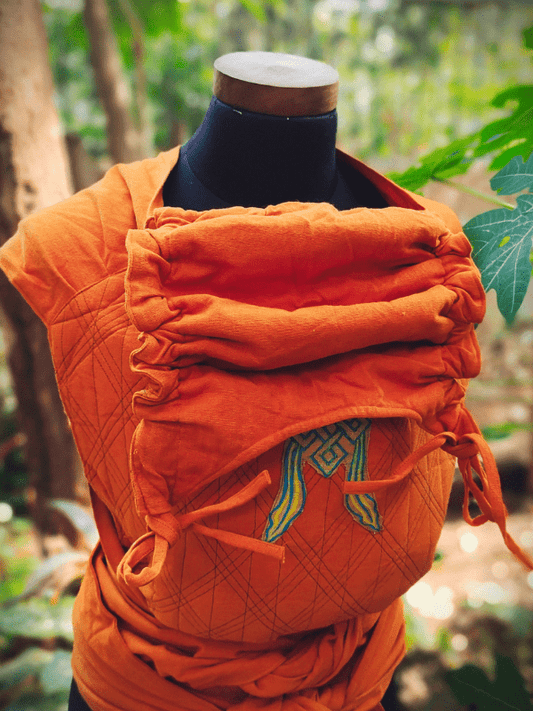 Frontal view of the Agni Meh Dai with adjustable wrap hood and pleated shoulders, styled on a mannequin against a forest backdrop.