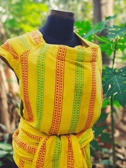 Close-up front view of the Nima wrap Meh Dai baby carrier by Almitra Tattva, showcasing its bold yellow fabric and vibrant Indian motif stripes.