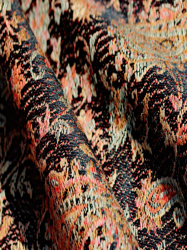 Close-up of Kalindi Ergonomic woven baby carrier featuring bold abstract floral patterns in black, rust, and sand tones, emphasizing durable breathable fabric ideal for ergonomic babywearing across seasons.