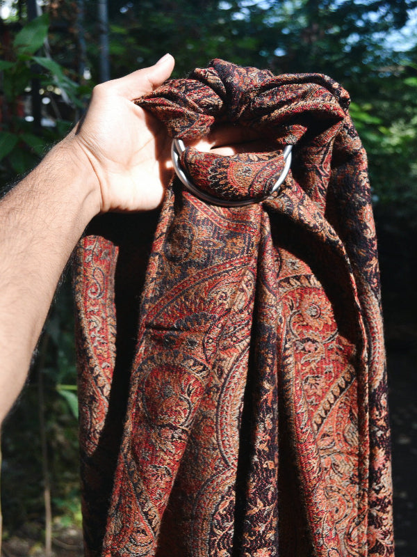 Hand holding Kalindi Ring Sling by Almitra Tattva, displaying safety-tested rings and the elegant woven cashmere blend in paisley-rich Jamawar style.