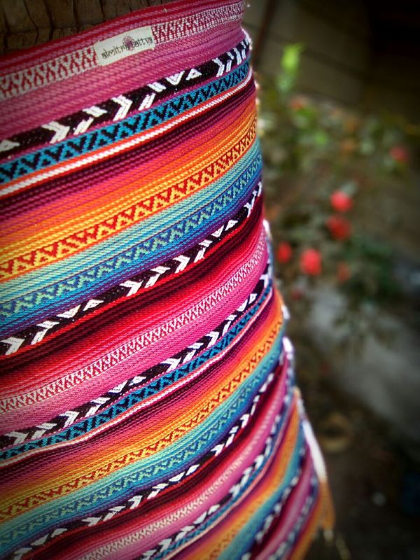 Close-up of a larona woven rainbow baby wrap sling featuring bold horizontal stripes in magenta, teal, orange, and black, showcasing textured cotton weave and breathable fabric, designed for ergonomic babywearing, newborn carrying, and hands-free parenting with a gender-neutral, artisan aesthetic.
