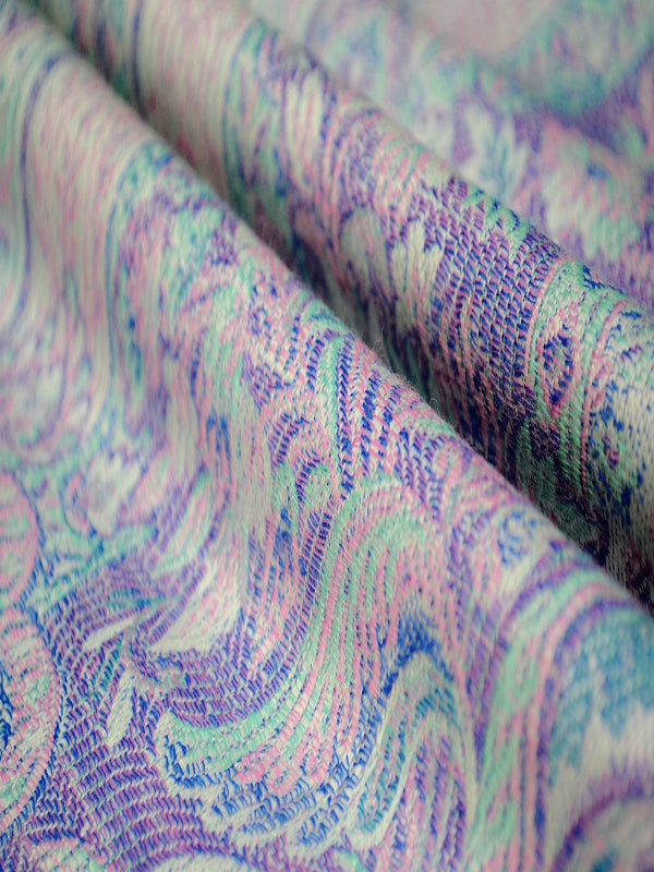 Detailed macro shot of Marisa White baby carrier fabric featuring a finely woven pastel paisley pattern in aqua, lavender, and soft blue tones, highlighting breathable texture, artisanal craftsmanship, and supportive structure for ergonomic babywearing.