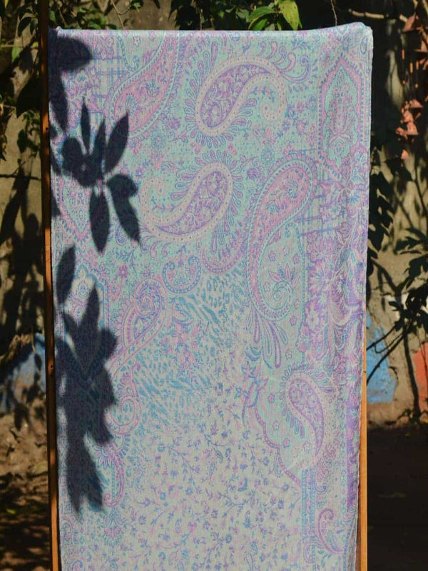 Full-length handwoven baby wrap displayed vertically outdoors, featuring a pastel paisley pattern in lilac and aqua tones, illustrating wrap length, drape, and breathable fabric ideal for newborn and toddler babywearing.
