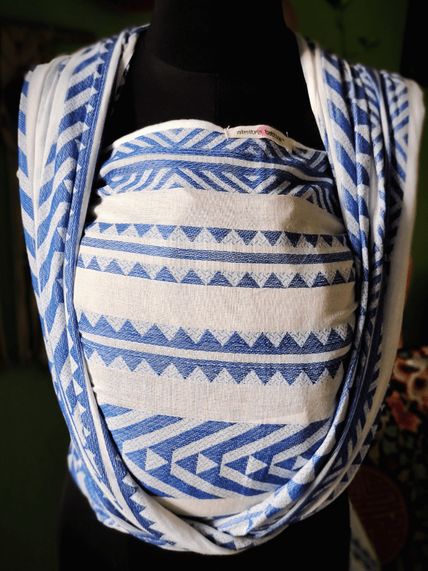 Close-up front view of Neelanjana newborn wrap sling, showing blue and white geometric woven fabric, deep seat panel, and soft shoulder passes, breathable baby carrier designed for ergonomic newborn support and conscious parenting.
