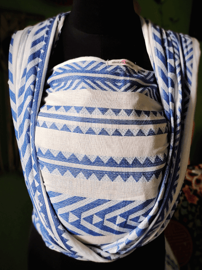 Close-up front view of Neelanjana newborn wrap sling, showing blue and white geometric woven fabric, deep seat panel, and soft shoulder passes, breathable baby carrier designed for ergonomic newborn support and conscious parenting.