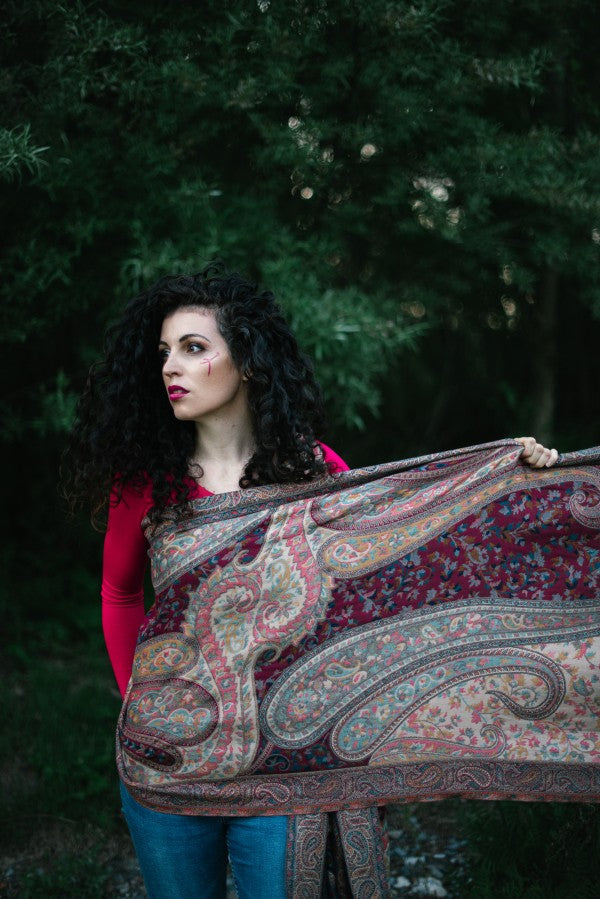 An unwrapped Nilofer, woven baby wrap with bold paisley and floral patterns in earthy reds and blues, showcasing lightweight breathable fabric ideal for ergonomic babywearing and hands-free parenting in natural settings.