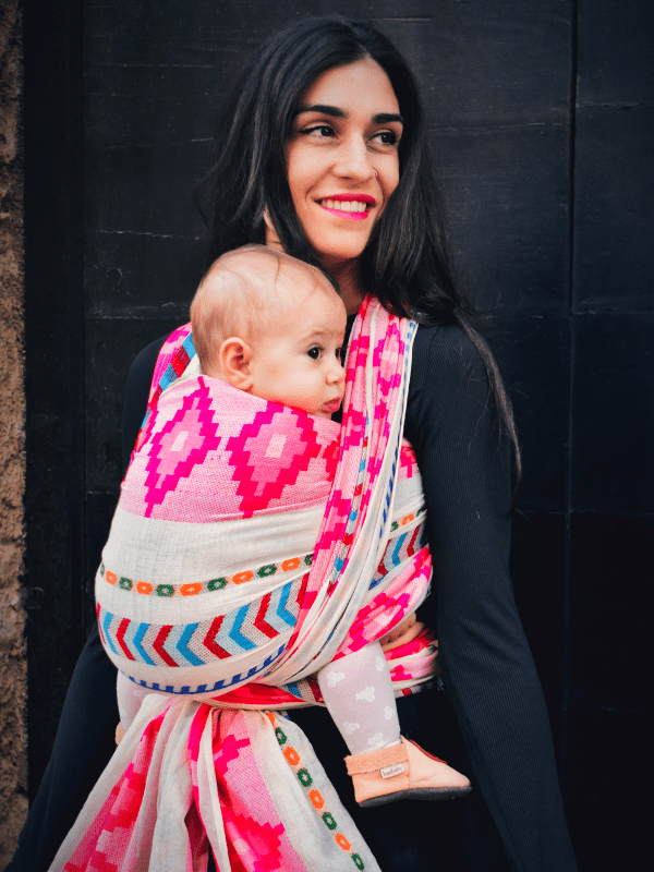 Close-up lifestyle image of Shubra newborn wrap carrier in use, showing infant supported in a front carry with soft woven cotton fabric, adjustable wrap tails, and ergonomic design for inclusive, hands-free parenting.