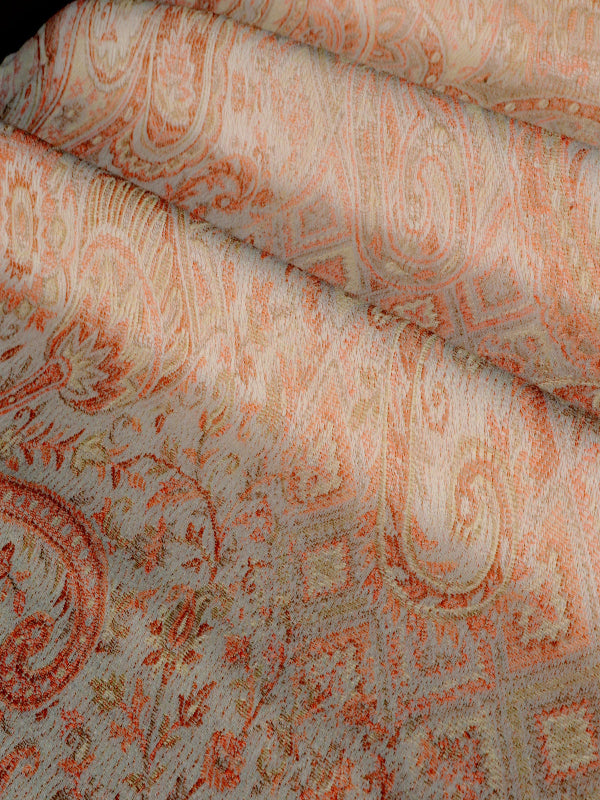 Close-up of Tushara baby wrap fabric featuring a warm ivory base with muted ember-orange woven motifs, showing fine handwoven texture and breathable structure, designed for ergonomic babywearing, newborn wraps, and hands-free parenting.