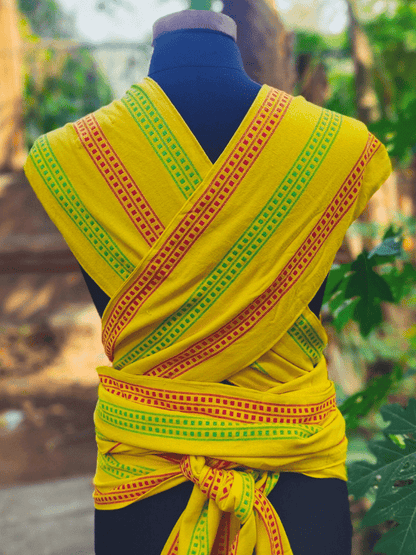 Back view of Nima Meh Dai baby carrier showing criss-crossed wide shoulder straps and supportive wrap tie, in bright yellow with festive Indian stripes.